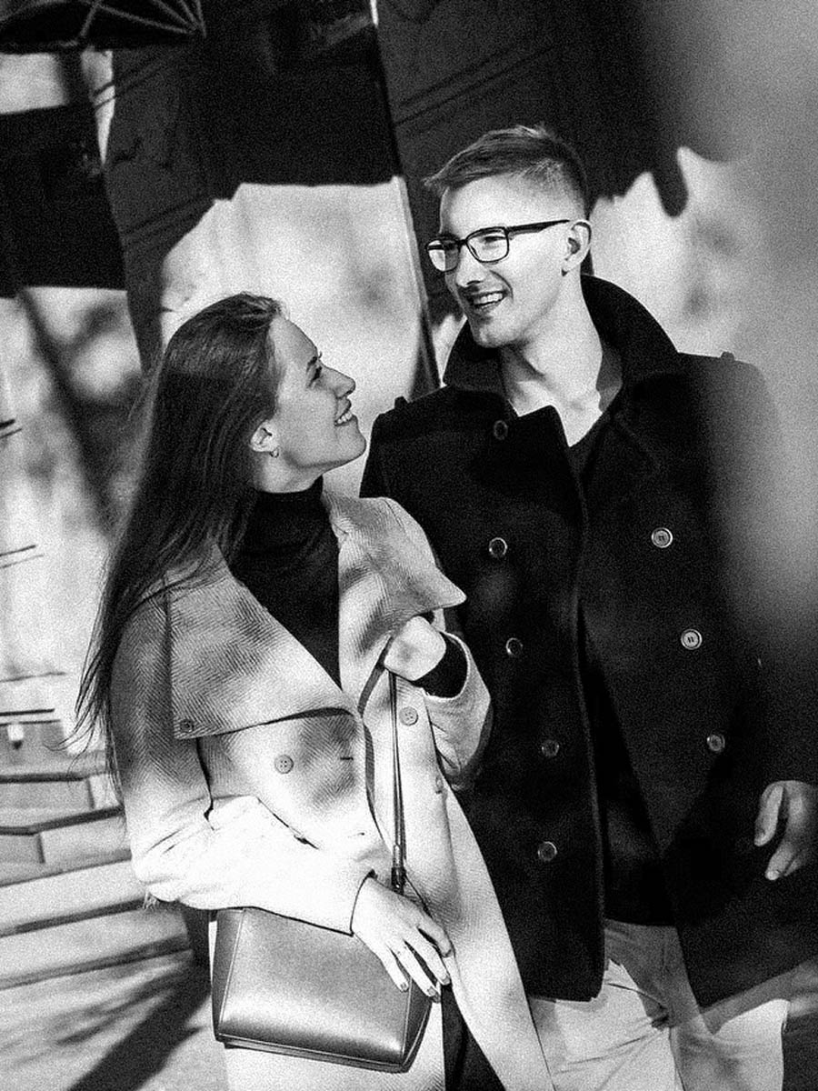 Wide environmental portrait of a couple against a textured city wall 10